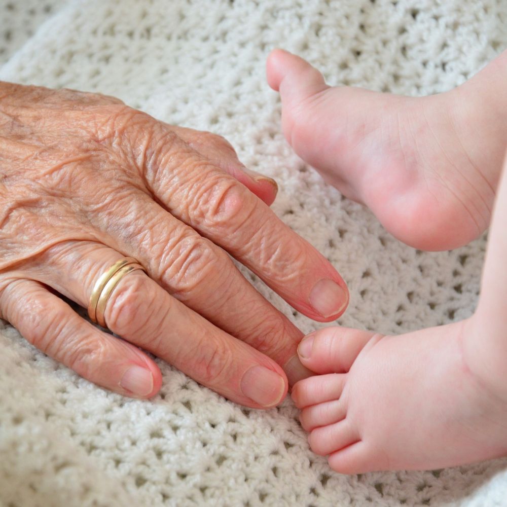 Ältere Hand berührt Babybeine